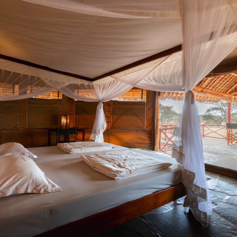 Luxuriöses Schlafzimmer in einer Safari-Lodge mit Blick auf die afrikanische Savanne.