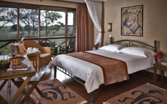 Hotelzimmer in Kenia mit Doppelbett und afrikanischen Dekoelementen.