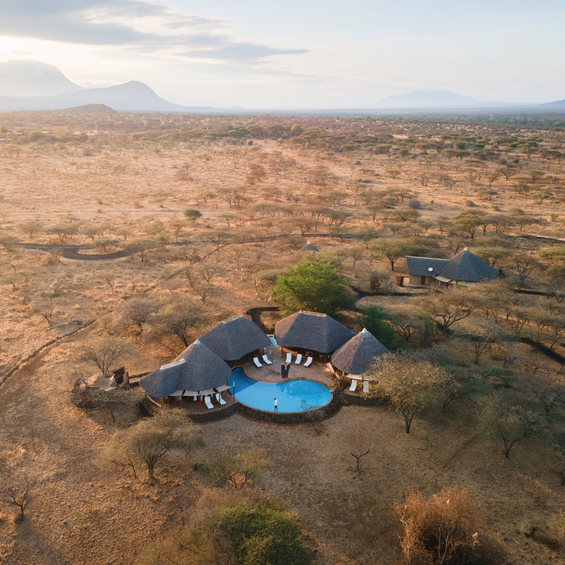 Luftaufnahme einer Safari-Lodge mit Pool in Kenias Savanne.