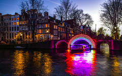 AMSTERDAM, NETHERLANDS - JANUARY 10, 2017: Cruise boats rush in night canals. Light installations on night canals of Amsterdam within Light Festival. January 10, 2017 in Amsterdam - Netherland.